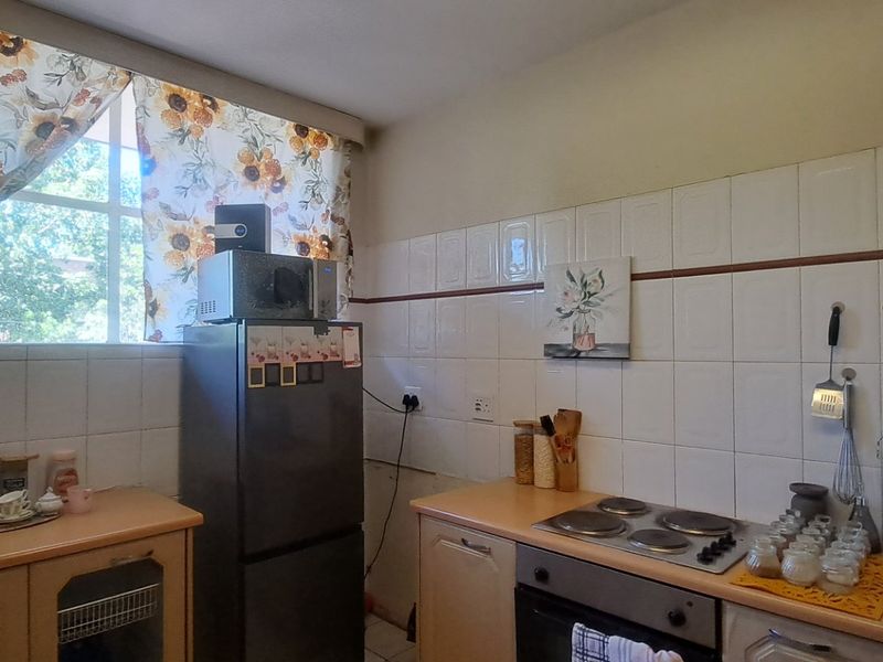A functional kitchen featuring built-in cabinetry, laminate countertops, an electric hob, and an oven with tiled splashbacks.