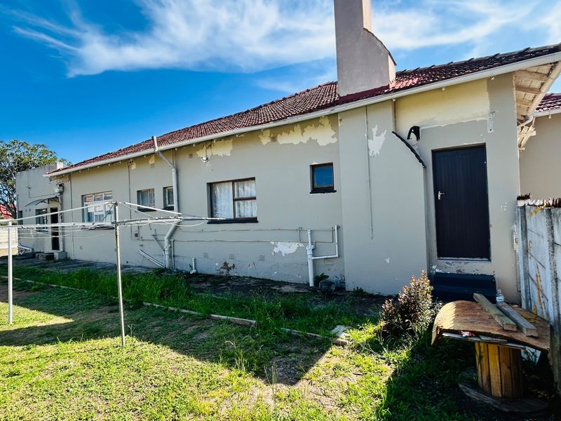 Rear exterior view of the commercial property showing a tiled roof, chimney, and significant peeling paint on the exterior walls.