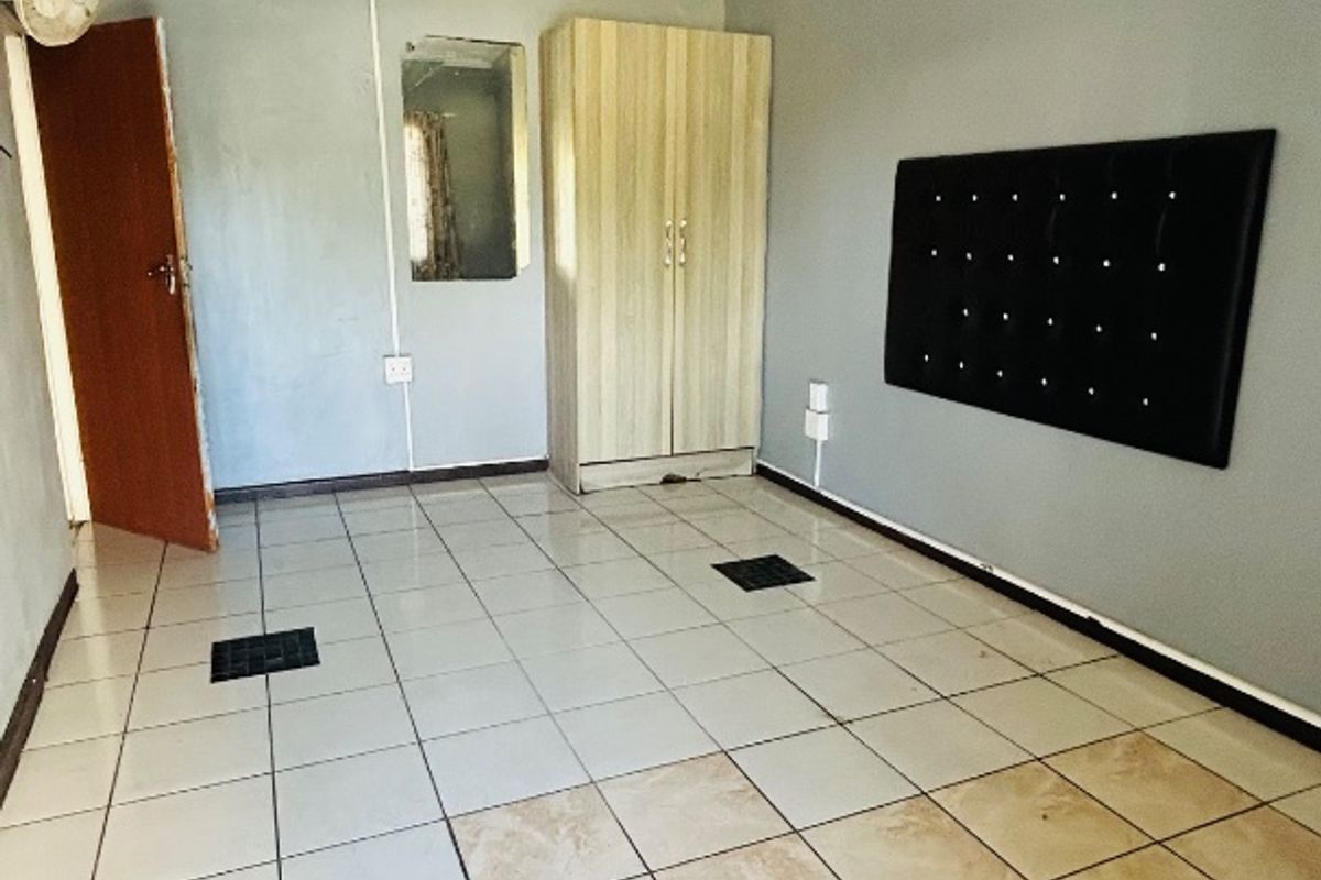 A vacant bedroom featuring tiled flooring, built-in storage, and basic lighting, offering a blank canvas for potential renovation and interior updates.
