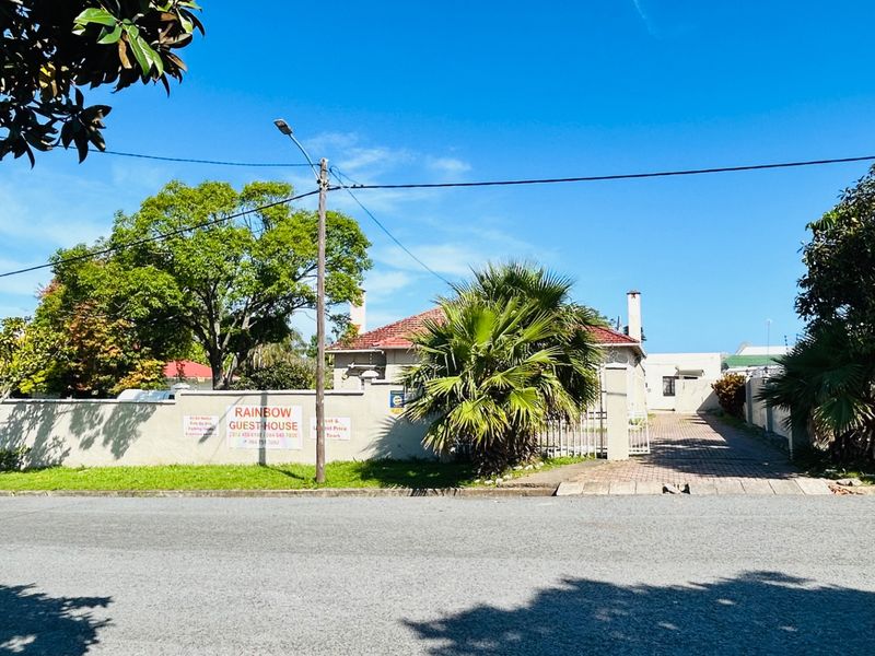 Street view of the commercial property featuring a gated entrance, paved driveway, and perimeter wall with signage.