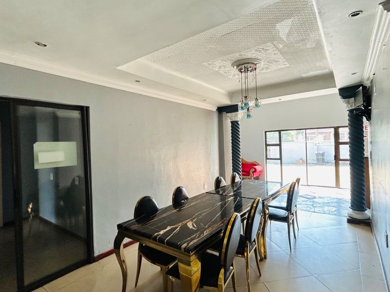 Spacious dining area featuring decorative columns, a recessed ceiling with a central medallion, and large sliding glass doors providing access to the exterior.