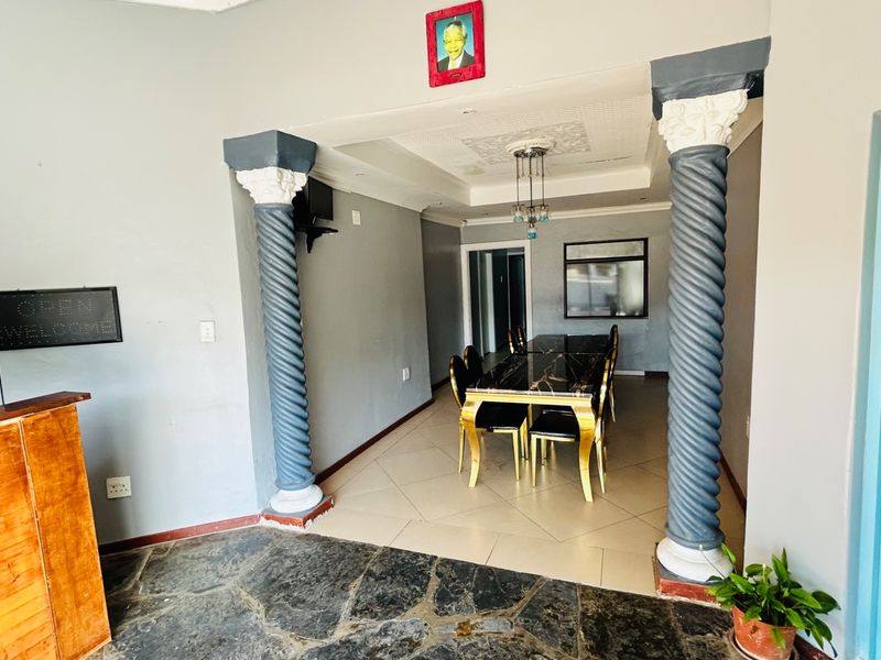 Dining area featuring decorative columns, tiled flooring, and a recessed ceiling with a central light fixture, creating a distinct transition between spaces.