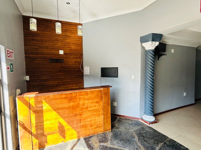 Commercial entry area featuring a built-in reception desk, decorative column, wood-paneled accent wall, and stone flooring.