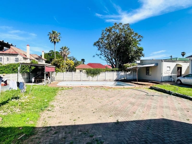 Outdoor pool area featuring a paved patio, swimming pool, and perimeter wall, offering potential for landscaping and exterior renovation.