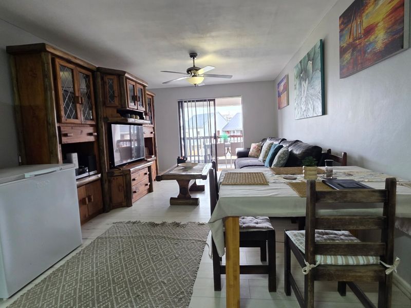 Open plan living and dining area featuring tiled flooring, a ceiling fan, and sliding glass door access to a balcony.