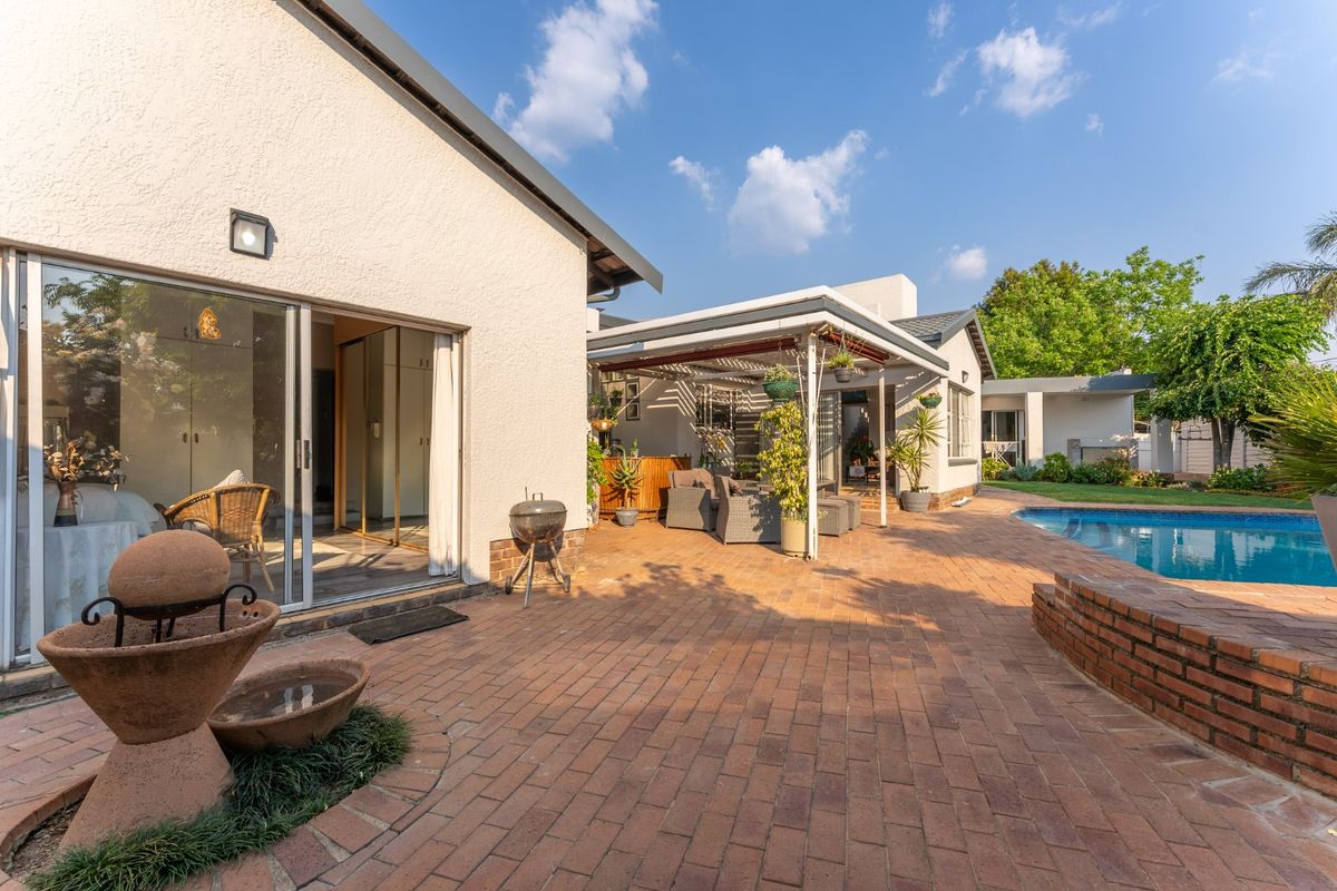 Spacious rear exterior featuring a brick-paved patio, a swimming pool with a brick retaining wall, and a covered outdoor entertainment area.
