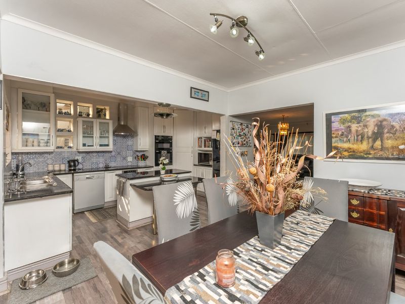 Open plan kitchen and dining area featuring built-in cabinetry, integrated appliances, a kitchen island, and modern laminate flooring.