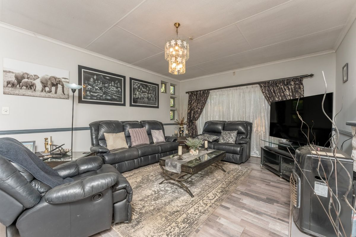 A comfortable living room featuring laminate flooring, a decorative chandelier, and a classic chair rail, providing a functional and inviting space.