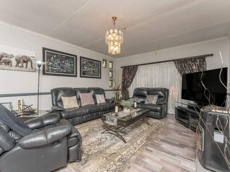 A comfortable living room featuring laminate flooring, a decorative chandelier, and a classic chair rail, providing a functional and inviting space.