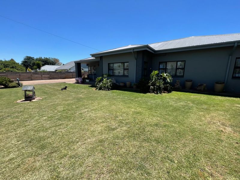A well-maintained rear garden featuring a spacious lawn, paved driveway, and a solid timber boundary fence, providing a private outdoor space.