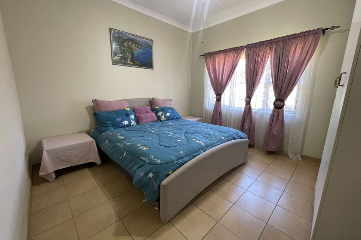 A functional bedroom featuring tiled flooring, a built-in cupboard, and a ceiling fan, offering a neutral base for personalization.