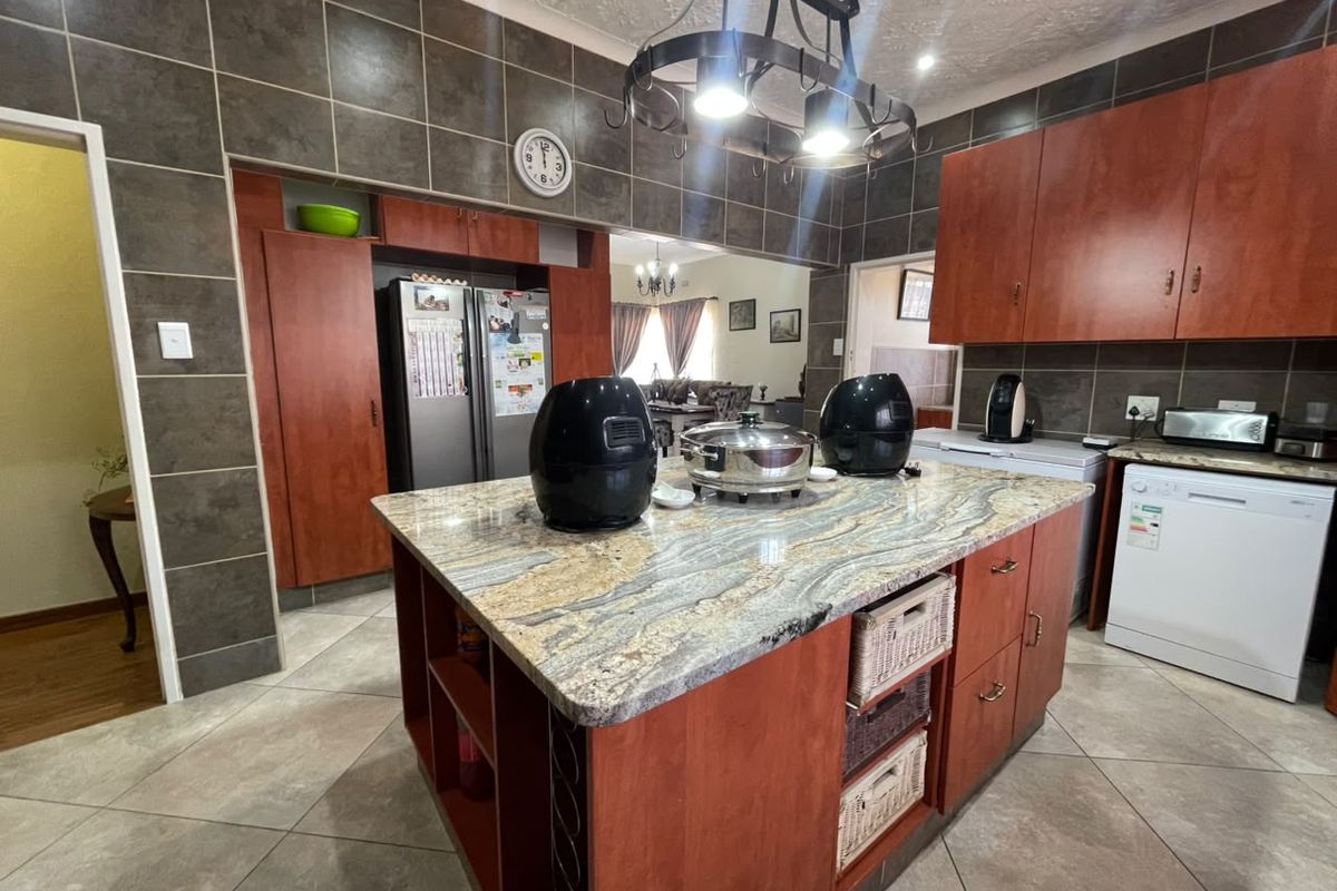 Spacious kitchen featuring a large central island with granite countertops, ample built-in cabinetry, and tiled finishes throughout.