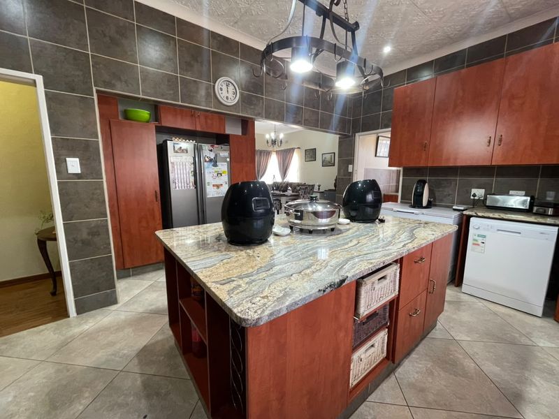 Spacious kitchen featuring a large central island with granite countertops, ample built-in cabinetry, and tiled finishes throughout.