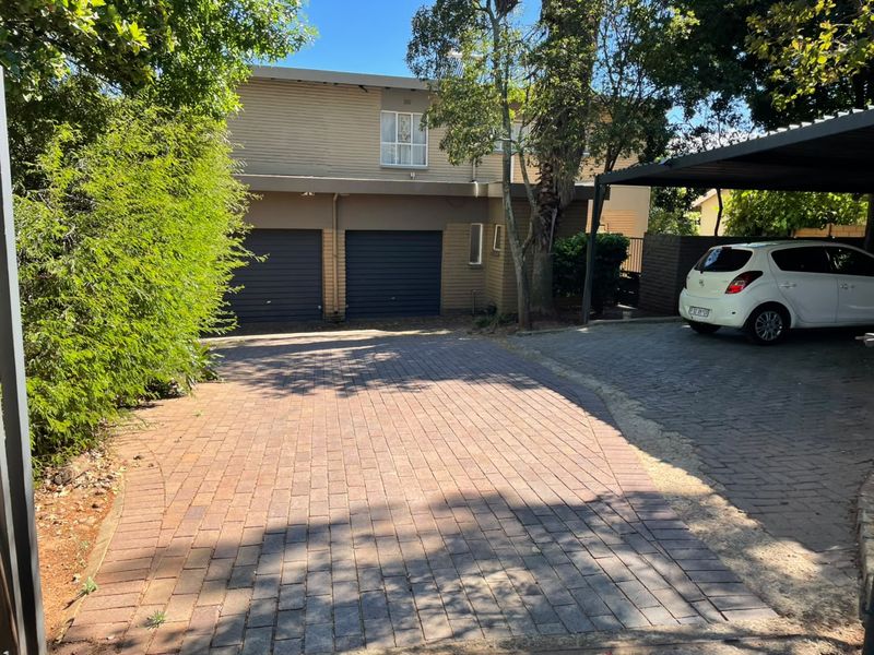 Front exterior view of the property featuring a paved driveway, double garage, and a covered carport area.