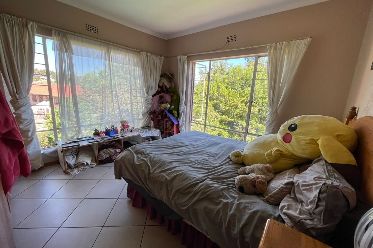 A bedroom featuring large windows with security bars, tiled flooring, and neutral wall finishes, offering ample natural light.