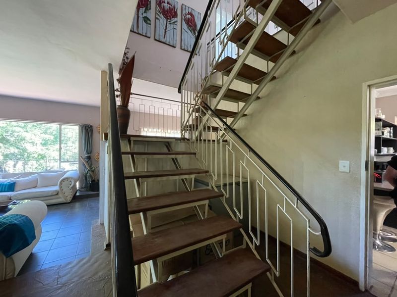 Interior hallway featuring an open-tread staircase with a metal balustrade and handrail, connecting different levels of the home.