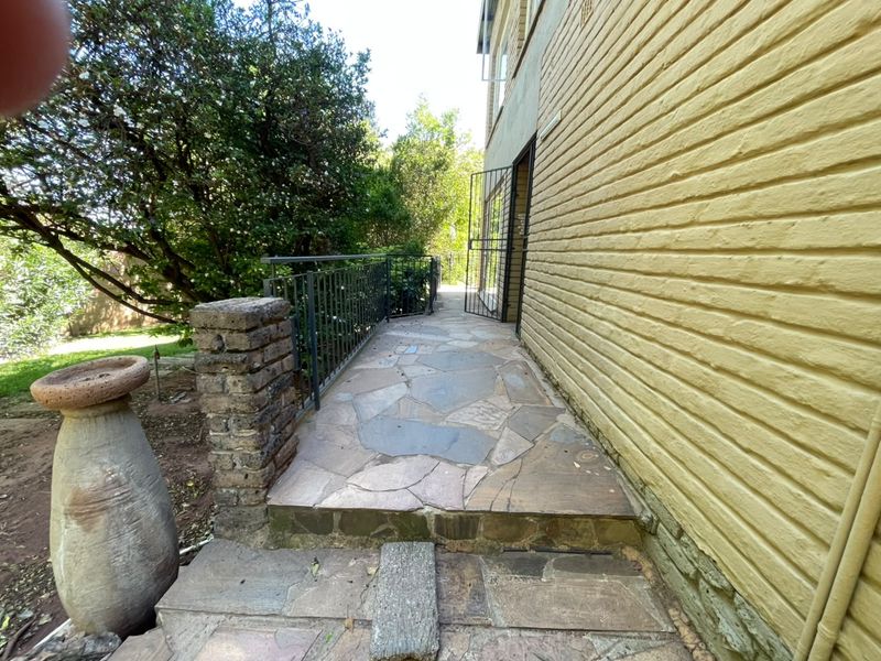 A stone-paved rear walkway featuring a metal railing and brick wall, providing access to the property's exterior.