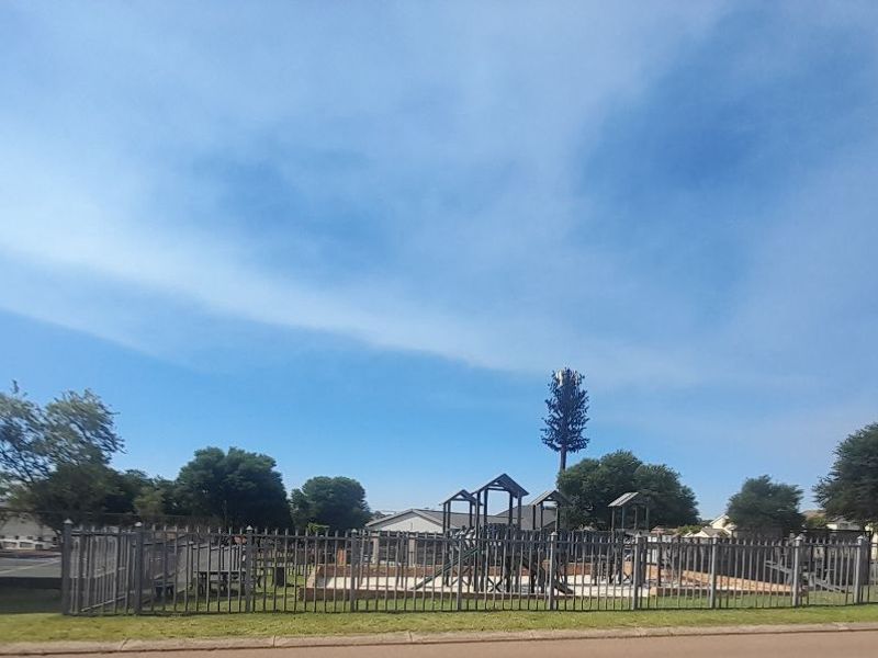 Communal recreational area featuring a fenced playground and tennis court within the residential estate.