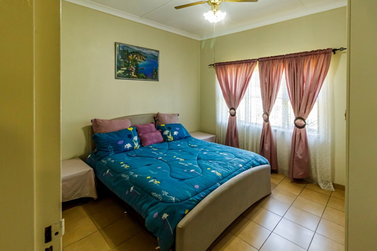 A functional bedroom featuring tiled flooring, a ceiling fan, and coved cornicing, providing a comfortable and well-maintained living space.