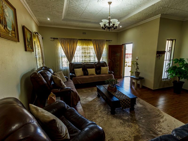 A spacious living room featuring classic timber flooring, a decorative pressed metal ceiling with a central rose, and direct access to the exterior.