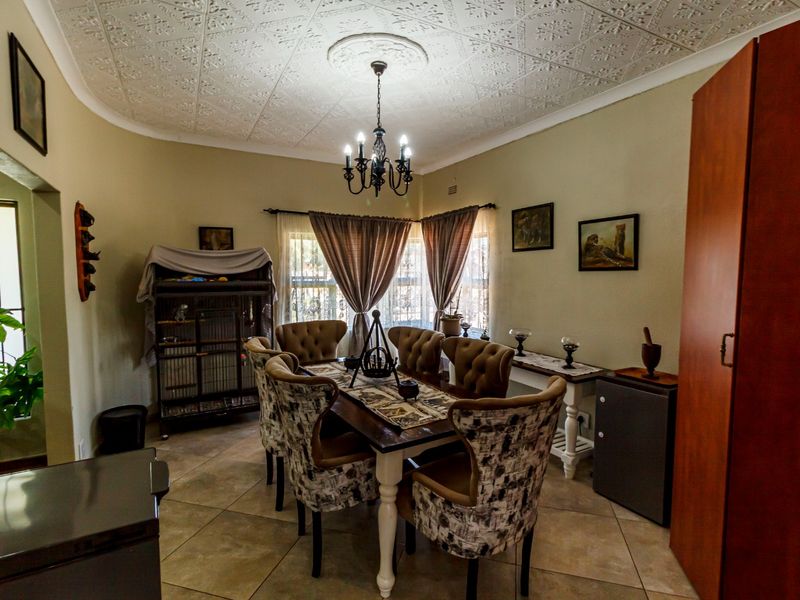 A dining room featuring a decorative pressed metal ceiling, a central chandelier, and tiled flooring, providing a classic and functional space for meals.