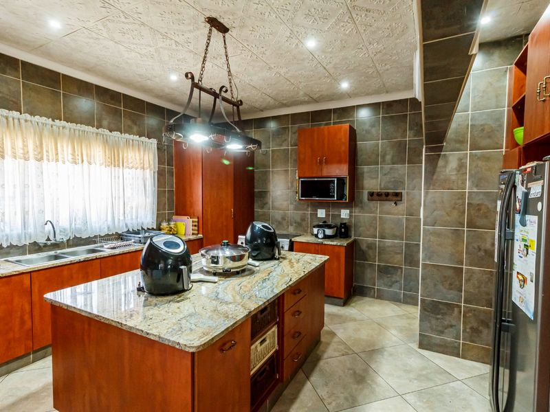 A spacious kitchen featuring granite countertops, a central island, extensive built-in cabinetry, and full-height wall tiling.