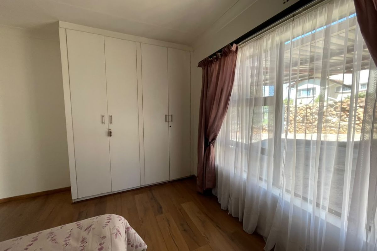 A well-lit bedroom featuring durable laminate flooring and ample built-in cupboard storage space.
