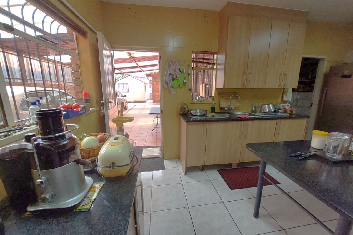 A functional kitchen featuring laminate cabinetry, granite countertops, and tiled flooring, with direct access to an outdoor patio area.