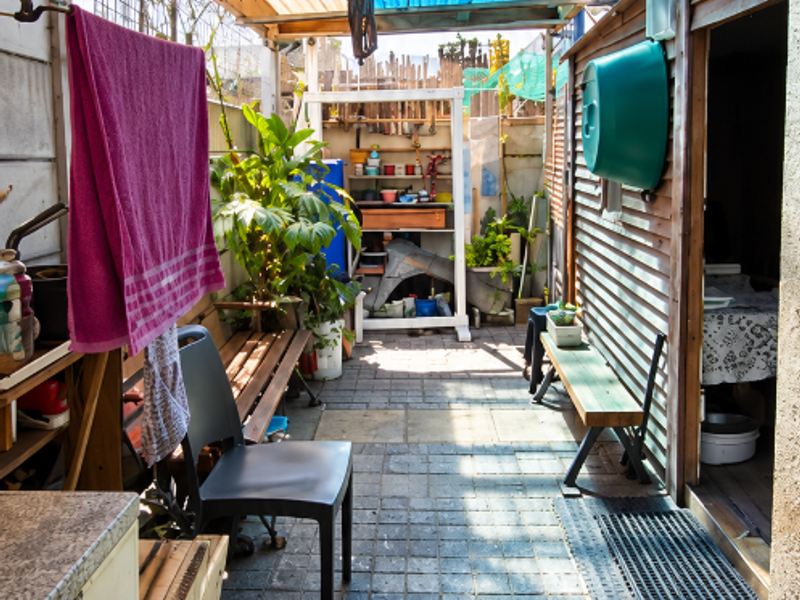 Covered outdoor patio area featuring a timber pergola structure with corrugated roofing and paved flooring, providing a functional utility or entertainment space.