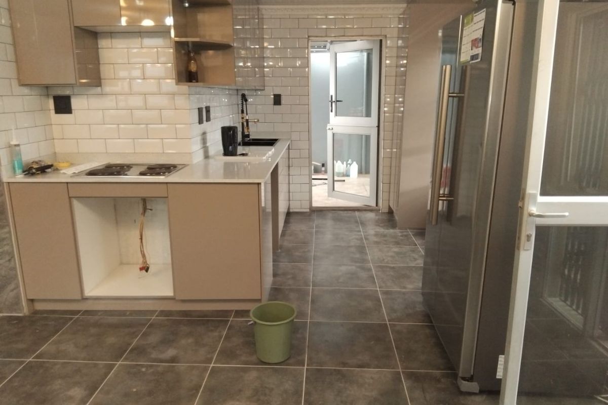 Modern kitchen featuring subway tile backsplash, quartz countertops, and dark floor tiles, currently awaiting installation of an under-counter oven.