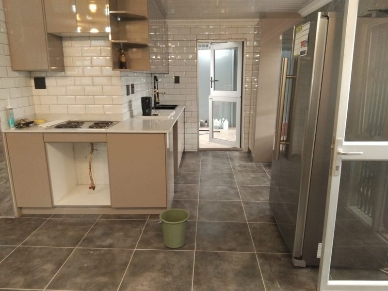 Modern kitchen featuring subway tile backsplash, quartz countertops, and dark floor tiles, currently awaiting installation of an under-counter oven.