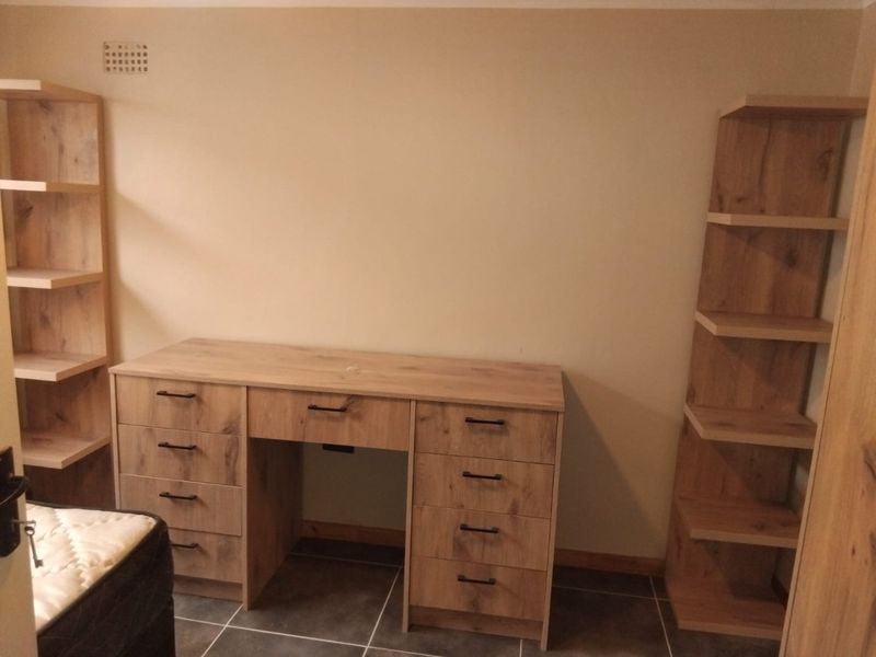 A functional home office space featuring built-in wooden desk and shelving units with modern hardware and tiled flooring.