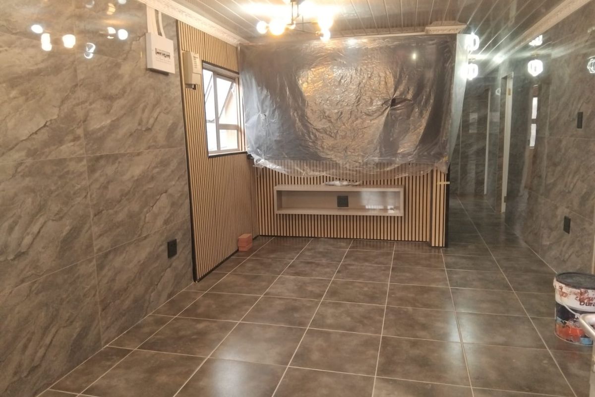 An interior living space featuring modern marble-effect wall tiles, slatted timber paneling, and a built-in floating shelf, currently undergoing final finishing touches.