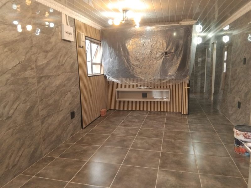 An interior living space featuring modern marble-effect wall tiles, slatted timber paneling, and a built-in floating shelf, currently undergoing final finishing touches.