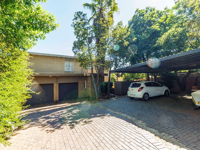 Front exterior view featuring a paved driveway, double garage, and a covered carport area.