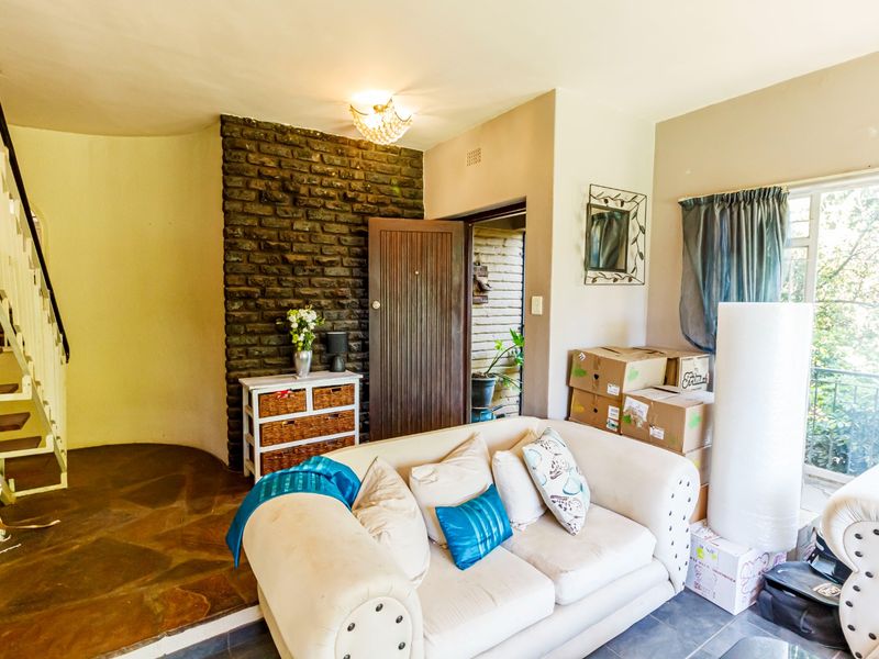 Living room featuring an exposed brick accent wall, stone flooring, and a staircase, offering a unique architectural character.