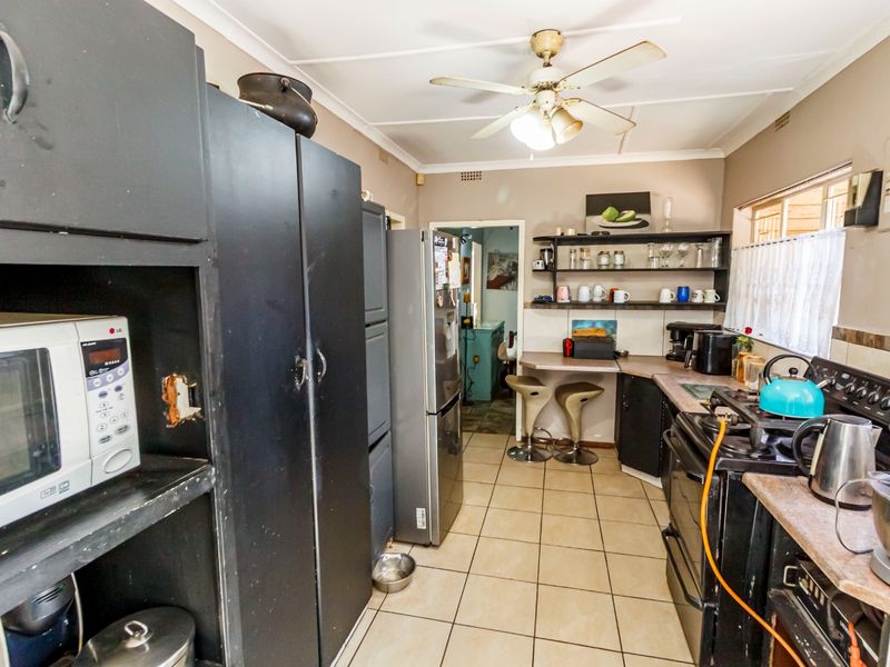 A functional kitchen featuring tiled flooring, built-in cabinetry, open shelving, and a gas stove, offering potential for modernization and aesthetic updates.