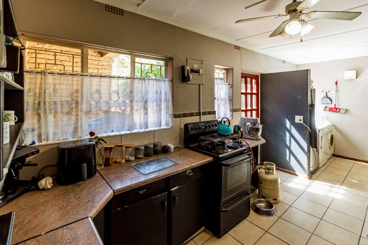 A functional kitchen featuring laminate countertops, built-in cabinetry, and a gas stove, with tiled flooring and a ceiling fan.
