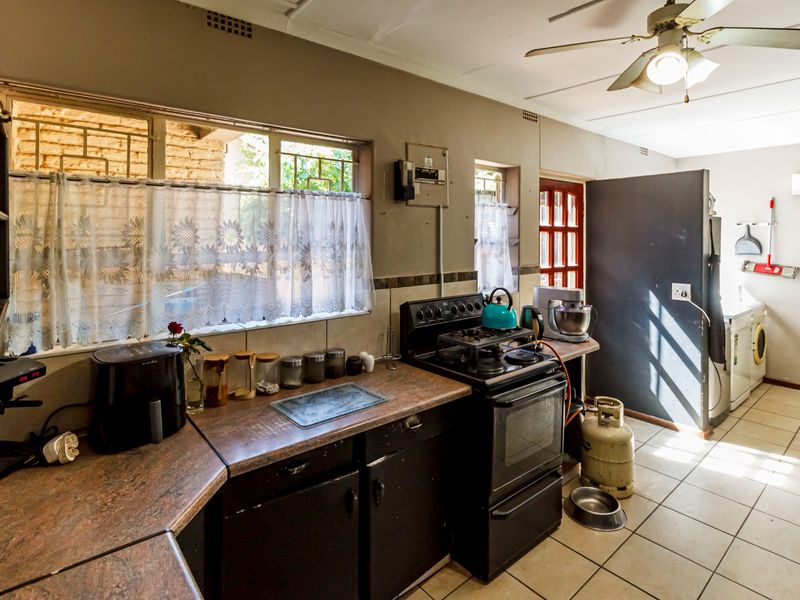 A functional kitchen featuring laminate countertops, built-in cabinetry, and a gas stove, with tiled flooring and a ceiling fan.