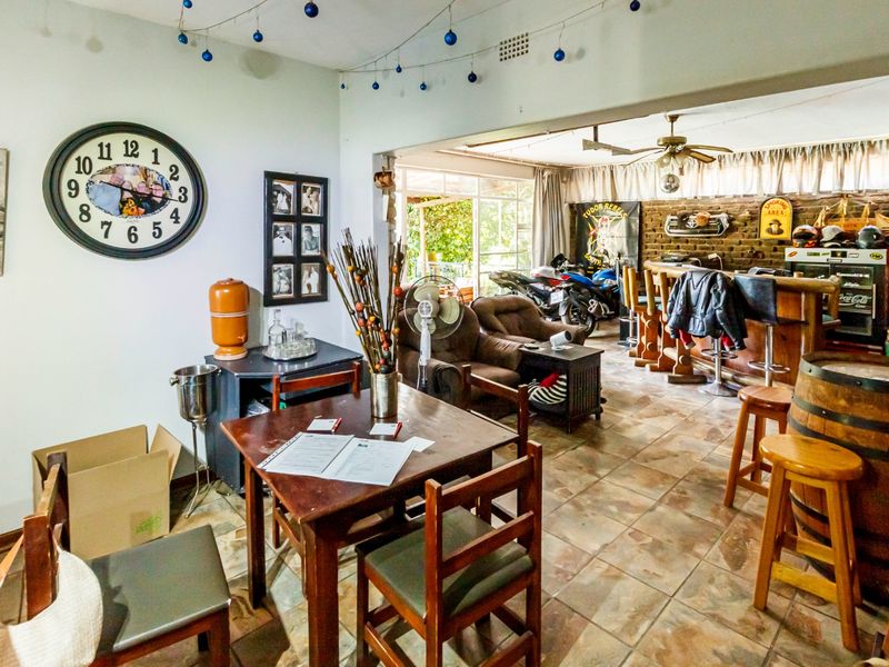 Open plan living area featuring tiled flooring, a built-in bar counter, and an exposed brick wall, creating a versatile space for entertaining.