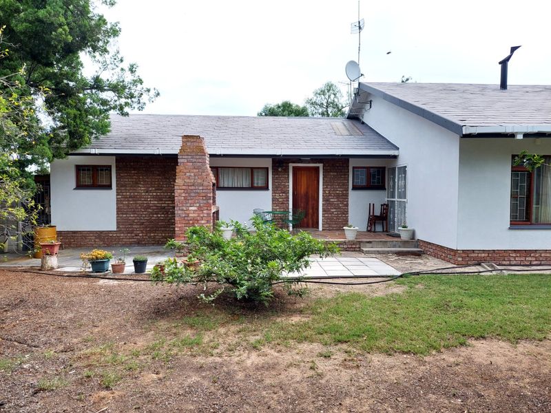 Rear view of the house featuring a paved patio area, a built-in brick braai, and a combination of brick and plastered wall finishes.