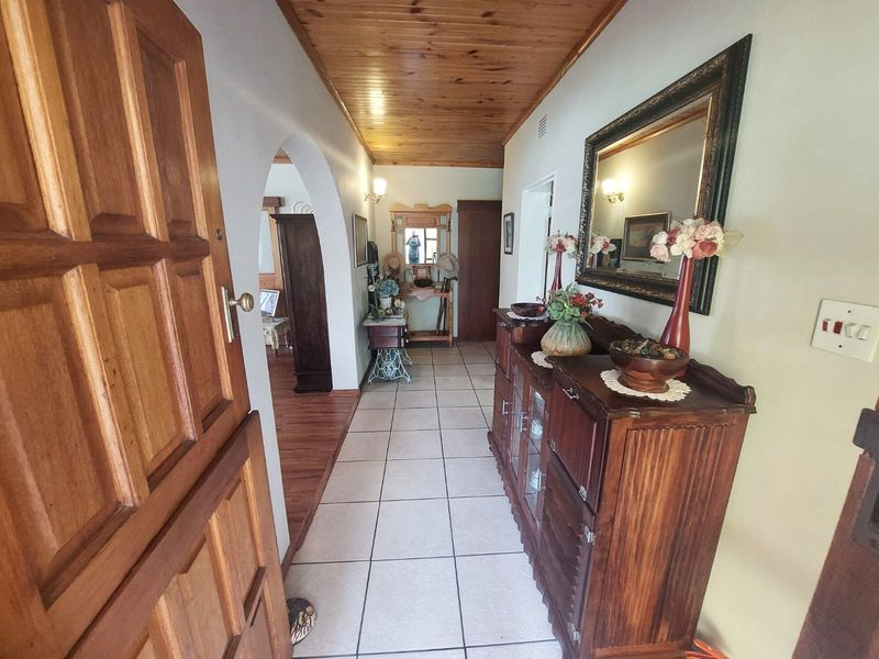 A welcoming entrance hallway featuring tiled flooring, a warm timber-paneled ceiling, and a classic arched doorway leading into the home.