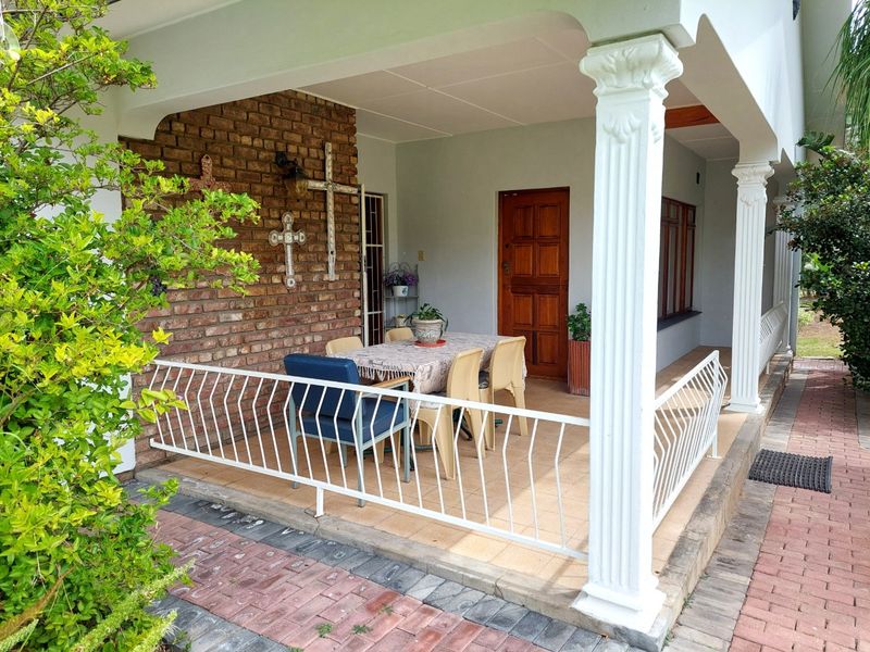 A covered patio area featuring a brick accent wall, decorative columns, and tiled flooring, providing a pleasant outdoor space for relaxation.