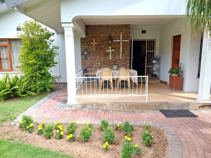 A covered patio area featuring a brick accent wall, tiled flooring, and a metal balustrade, providing a functional outdoor space for relaxation.