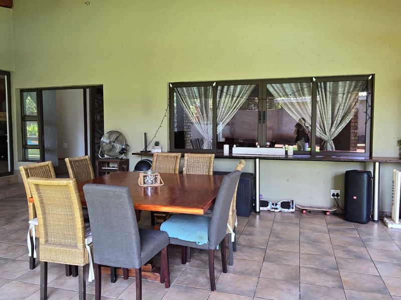 A spacious covered patio area featuring tiled flooring, aluminium window frames, and a built-in counter, ideal for outdoor dining and entertaining.
