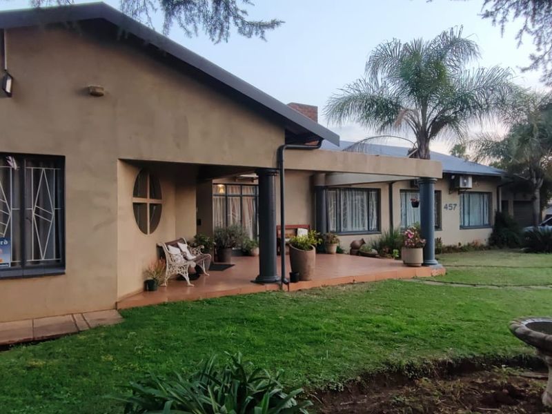 A single-story residential property featuring a covered front patio, security-barred windows, and a well-maintained garden with a paved driveway.