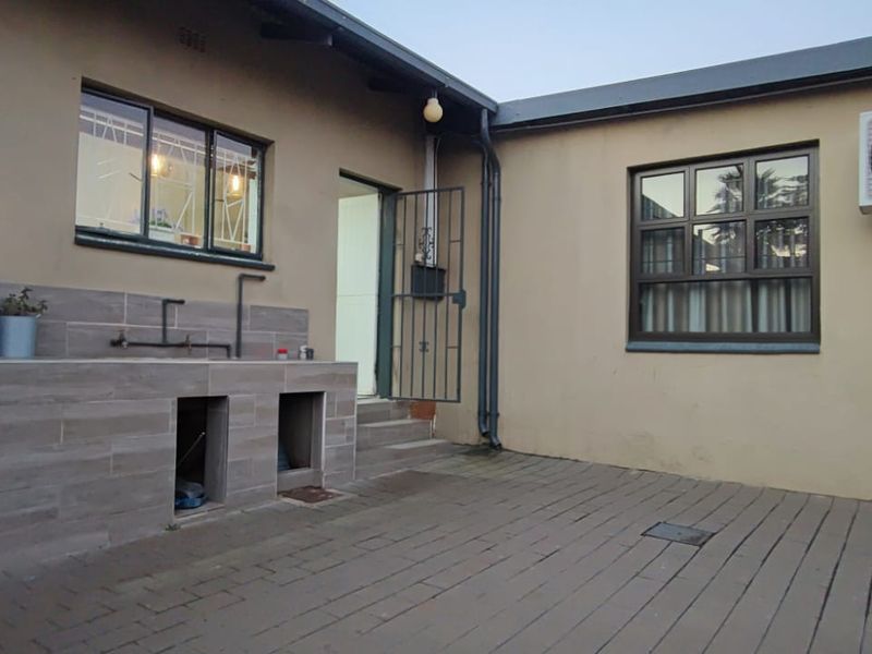 Rear exterior area featuring a paved patio, a built-in tiled outdoor sink, and an installed air conditioning unit.