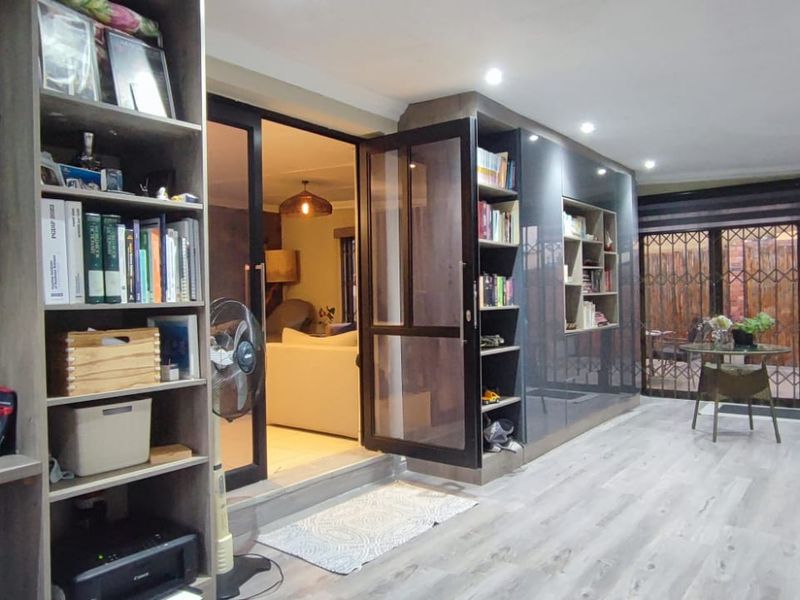 A modern living area featuring laminate flooring, recessed lighting, and extensive built-in cabinetry, with direct access to an outdoor patio through sliding glass doors.