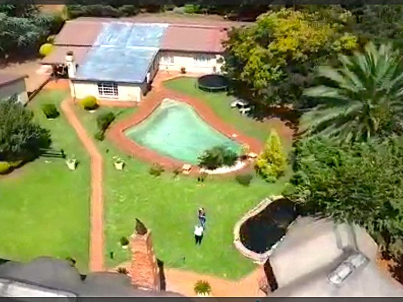 Aerial view of the farm property featuring a swimming pool, landscaped garden, paved pathways, and a pond set within a spacious outdoor area.