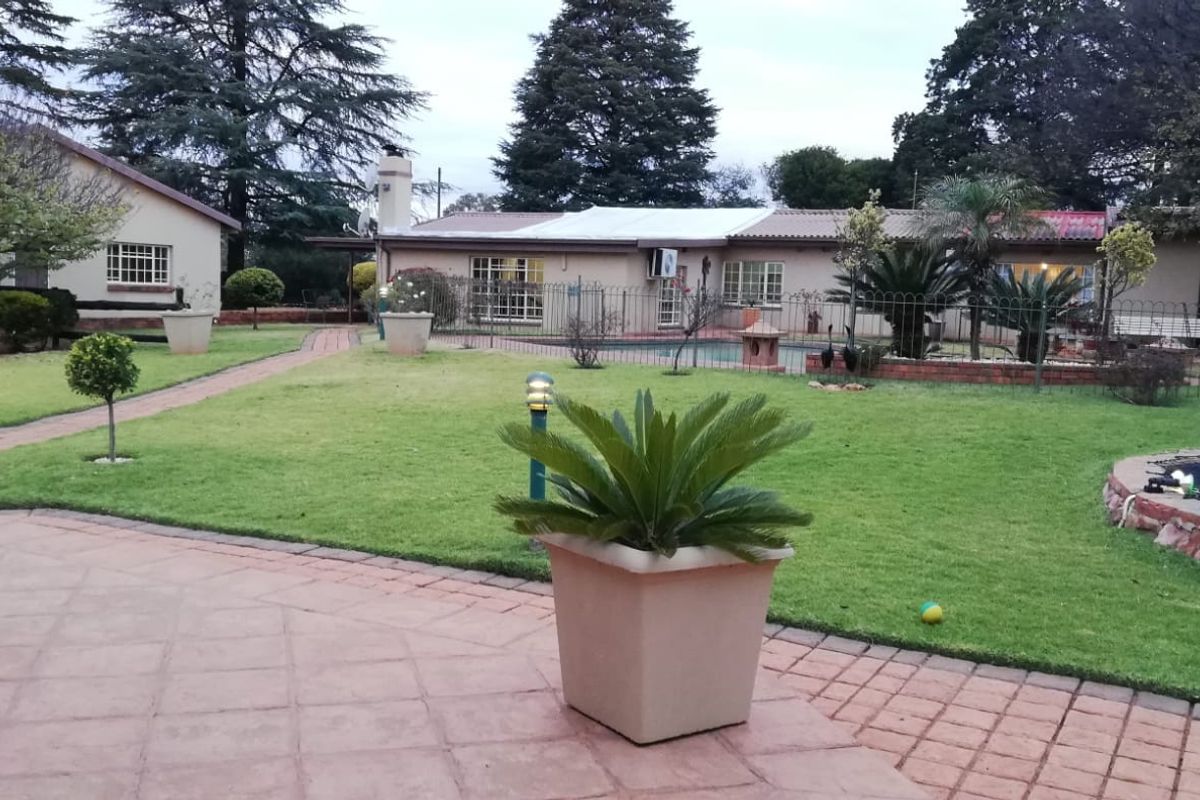 Spacious rear garden featuring a paved patio area, well-maintained lawn, and a swimming pool, providing an ideal setting for outdoor relaxation and entertainment.